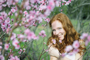 beautiful red-haired girl among the flowering trees