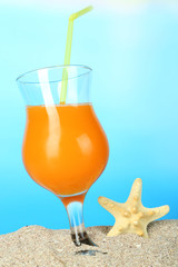 Beach cocktail in sand on blue background