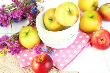 Juicy apples on plate on white wooden table