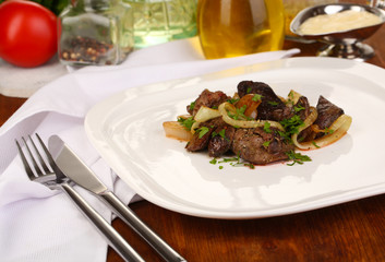 Fried chicken livers on plate on wooden table close-up