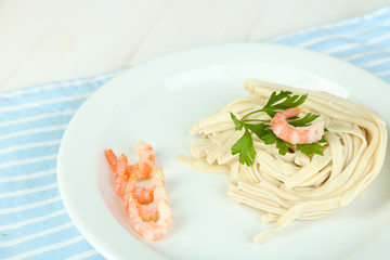 Pasta with shrimps on white plate, on wooden background