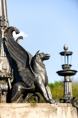 sculpture of griffin on stone pedestal in autumn sunny day