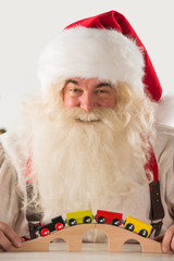 Santa Claus sitting and playing with railway toy at home
