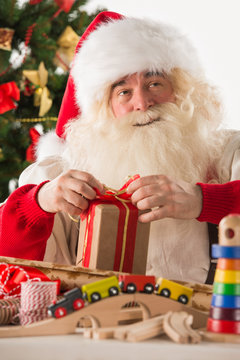 Santa Claus working - preparing and wrapping christmas gifts