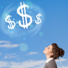 Young girl pointing at dollar sign clouds on blue sky