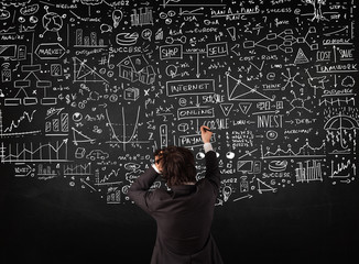 Businessman standing in front of drawn charts on a blackboard