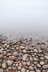 Coastal stones on Saimaa lake in foggy morning