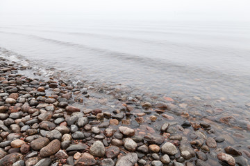 Stones on Saimaa lake coast in foggy morning