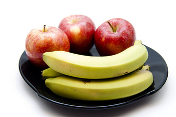 Äpfel mit Bananen auf schwarzen Teller