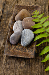 zen stones and fern leaf on wooden board