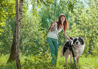 Naklejka na ściany i meble Cute young woman with her Dog in the summer forest