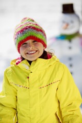 Winter fun, happy kid playing with snowman