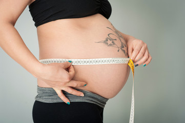 Pregnant woman measuring belly.