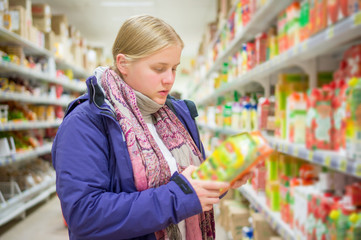 Young woman select juices on shelves in supermarket