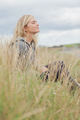 Side view of cute thoughtful woman sitting at beach