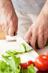 Obraz na płótnie Canvas man cutting vegetables for salad
