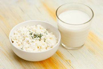 Healthy breakfast. Bowl of cottage curd and a glass of milk on vintage wooden table 