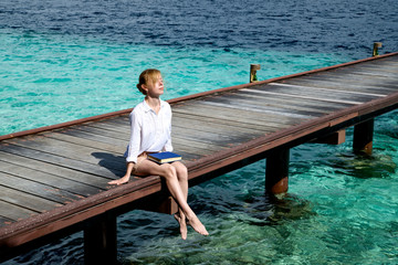 Girl is relaxing on a pier in the ocean