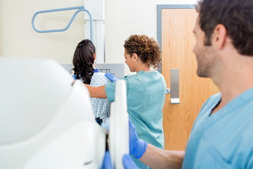 Nurse Adjusting Xray Machine In Examination Room