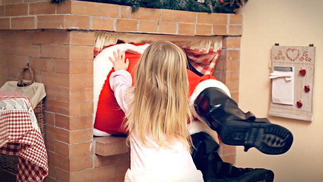 Christmas Eve little girl push Santa Claus in fireplace