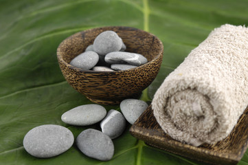 towel in bowl and zen stones in bowl on green leaf