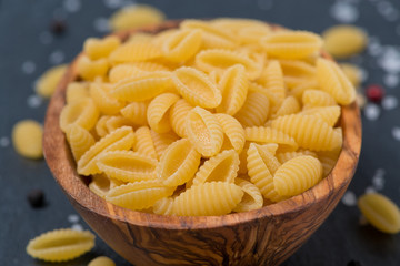 Italian pasta shells in a wodden bowl, close-up, selective focus