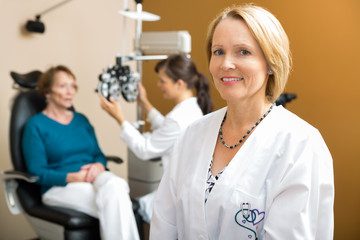 Confident Eye Doctor With Colleague Examining Patient