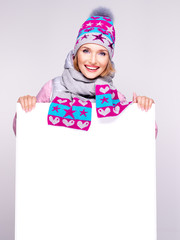 Adult smiling  woman in winter hat holds the white banner