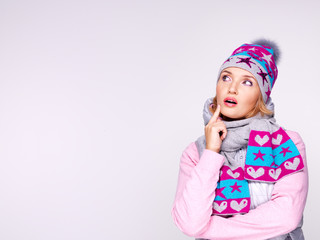 Photo of a thinking girl in winter clothes looking up