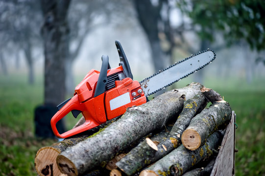 gasoline powered professional chainsaw on pile of cut wood