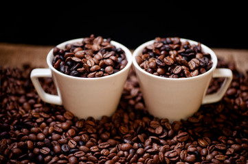 Fresh hot columbian coffee in two cups, around coffee beans