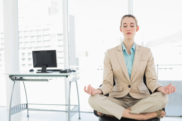 Concentrated calm businesswoman sitting in lotus position on her