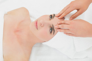 Hands massaging woman's forehead at beauty spa