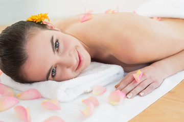 Obraz na płótnie Canvas Beautiful woman resting on towel with petals at beauty spa