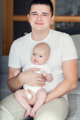 father with cute baby on the couch at home