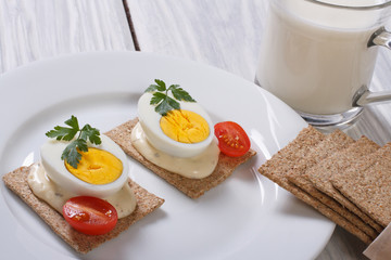 Cracker with a boiled egg, sauce and cherry tomatoes