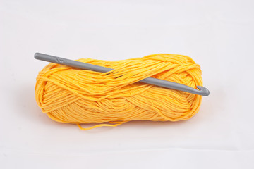 Yellow skein and crochet on white background