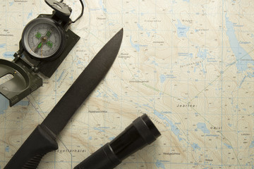 Fototapeta na wymiar Compass, knife and flashlight on map