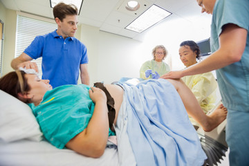 Man Looking At Medical Team Operating Pregnant Woman
