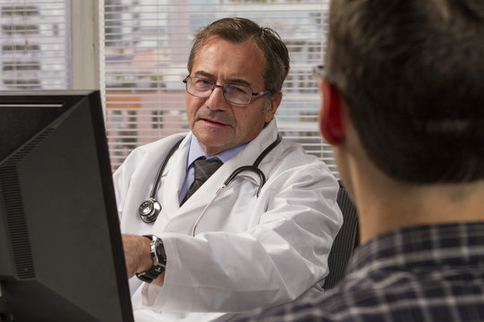 Doctor using computer while consulting with his patient