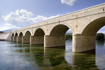 Fototapeta na wymiar Ancient stone arch bridge over the river Cetina in Croatia