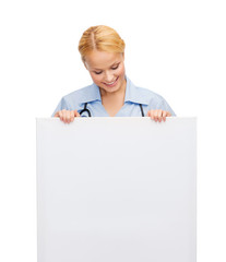Fototapeta premium smiling female doctor or nurse with blank board