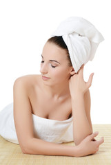The beautiful woman in a towel on bamboo rug. SPA concept.