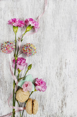 Pink carnation flower and sweets on wooden table. Top view, copy