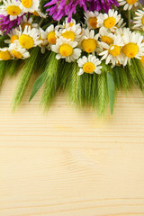 Wild flowers and green spikelets, on wooden background