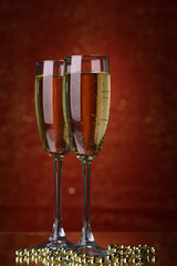 Two glasses of champagne on bright background with lights