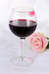 Glass of wine with lipstick imprint on white fabric background