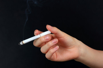 Woman hand holding cigarette with smoke, isolated on black
