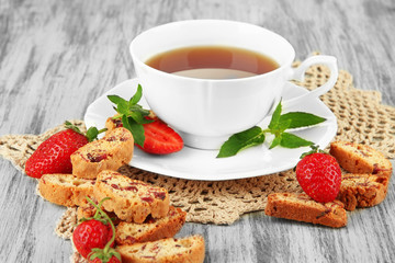 Cup of tea with cookies and strawberries on table close-up