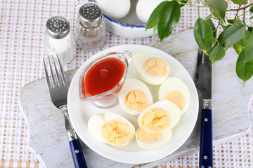 Boiled eggs on plate on wooden board on tablecloth